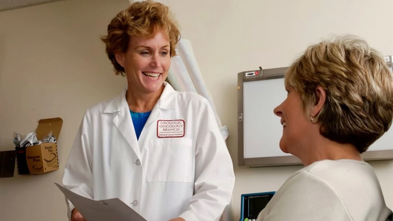 Doctor in clean white lab coat reviewing clinical records with patient in bright daylight consultation room